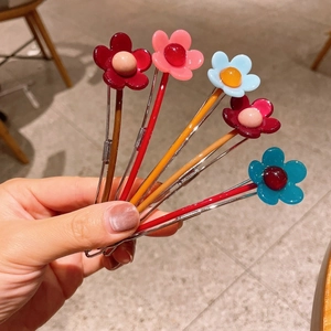 Dettaglio di cinque fermagli per capelli in resina a forma di fiori in vari colori vivaci