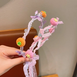 Detail eines rosa-violetten Haarreifens mit Perlen und Fruchtanhängern
