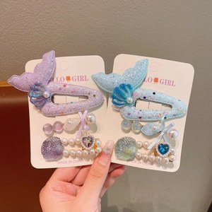 Detail of mermaid tail hair clips with shells, bows and pearls in purple and blue colors