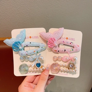 Detail of mermaid hair clips with sequins, shells, and faux pearls in pink and blue