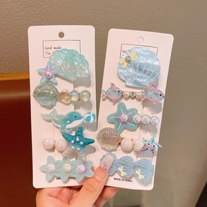 Detail of ocean-themed hair clip set with shells, starfish, and pearls on a display card