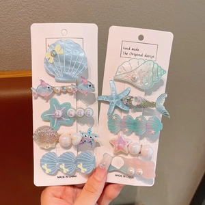 Close-up of ocean-themed shell and starfish hair clips with iridescent resin and pearls