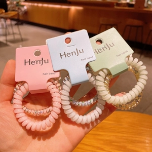 Dettaglio di elastici per capelli a spirale pastello in rosa, blu e verde su schede