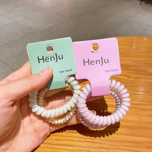 Dettaglio degli elastici a spirale per capelli a filo del telefono in rosa e panna