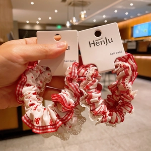Detail of red and white checkered scrunchies with lace edges on cardboard packaging