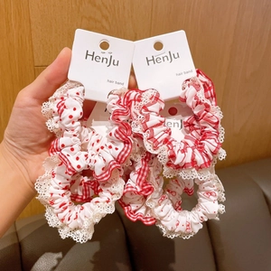 Close-up of four red and white hair scrunchies with lace trim and polka dot patterns