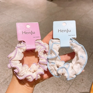 Detail of floral fabric scrunchies in purple and blue with decorative card packaging
