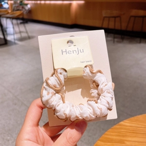 Detail of white scrunchie with brown heart patterns and elegant scalloped lace edges