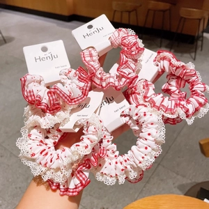 Close-up of red and white polka dot and plaid hair scrunchies with delicate lace trim
