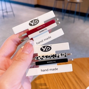 Close-up of four minimalist acetate hair clips in burgundy, ivory, and cow print patterns