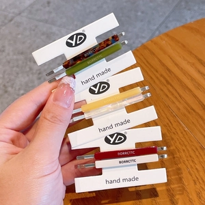 Collection of colorful long acetate hair clips with brand lettering on a display card