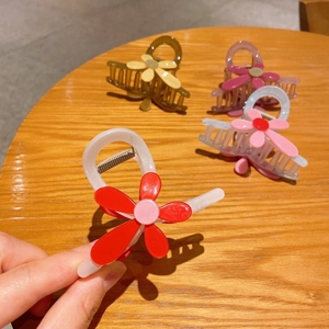 Pinces à cheveux fleurs moyennes en quatre couleurs sur table en bois pour coiffure