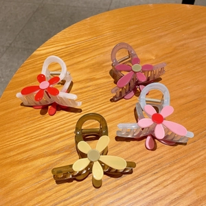 Lot de quatre pinces à cheveux fleur en résine colorée sur un bureau en bois