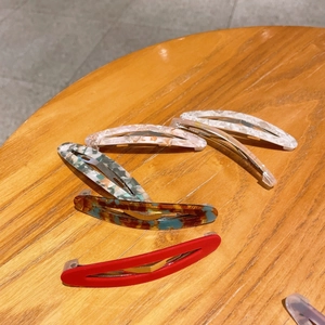 Détail de pinces à cheveux en acétate avec ressorts métalliques sur fond de bois