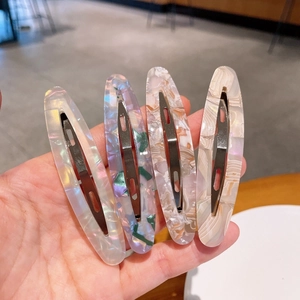 Gros plan de quatre barrettes évidées en acétate coloré avec des textures marbrées