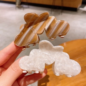 Detail of marble-textured heart-shaped acetate hair claws in brown amber and creamy white
