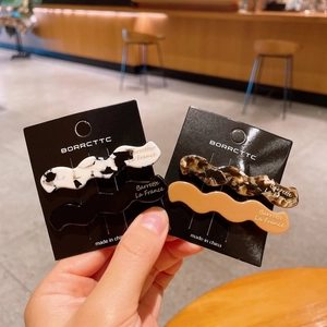 Detail view of 4-piece wavy acetate hair clips set in marble and tortoiseshell patterns
