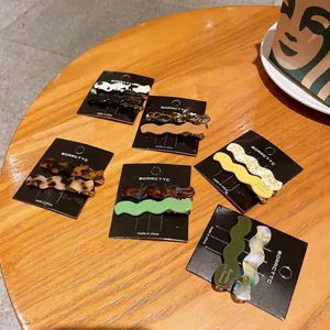 Detail view of wavy acetate hair clips in assorted colors on a black display card