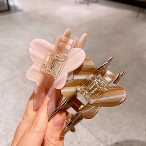 Macro detail of butterfly hair claw clips in pink and amber acetate marble texture