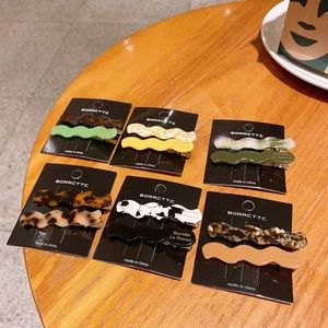 Set of wavy acetate hair clips with various patterns on a warm wooden background