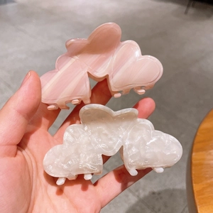Detail of elegant heart-shaped acetate hair claws in pearly white and marble pink