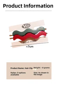 Detail view of wavy acetate hair clips in green and red with gold label, 7cm length