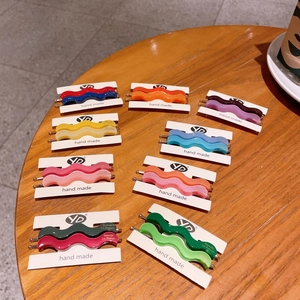 Colorful wavy matte acetate hair clips in pastel shades displayed on a paper card