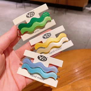 Close-up of wavy acetate hair clips in multiple colors on a branded display card