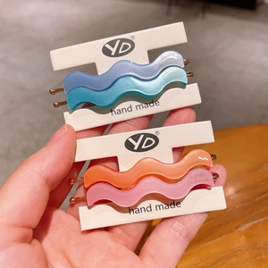Close-up of matte wave hair clips in blue, cyan, orange and pink on white cardboards
