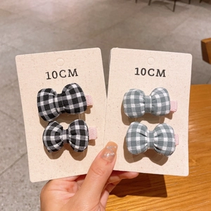 Detailed view of handmade checkered bow hair clips on display cards in neutral tones