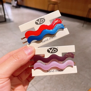 Wavy acetate hair clips set in red, blue, and purple with gold logo accent