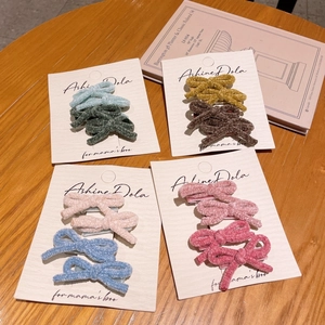 Detail of plush bow hair clips in multiple colors on cards with warm wooden background