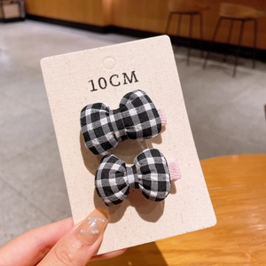 Detail of two black and white checkered bow hair clips on a 10cm display card