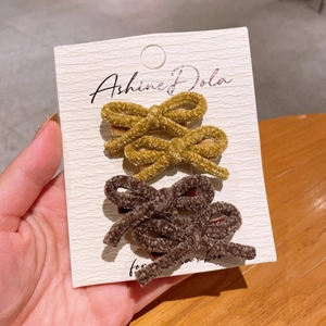 Detail of four velvet bow hair clips in yellow and brown on a white display card