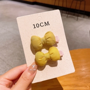 Detail showing high quality cotton fabric of a 10cm yellow bow hair clip for children