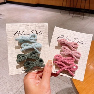 Cute velvet bow hair clips set in pink and green colors on a white display card