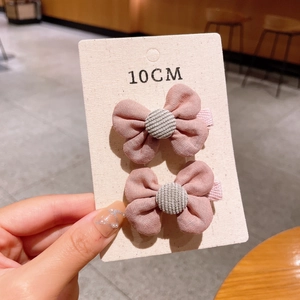 Detail of pink cotton bow hair clips with grey textured center on a paper card