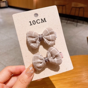 Detail of 10cm handmade light brown checkered bow hair clips on a fabric display card