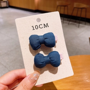 Detail of dark blue fabric bow hair clips with soft cotton texture on display card