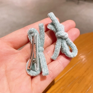 Detail view of two light blue plush bow hair clips with soft chenille texture and metal base