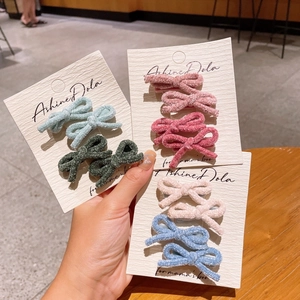 Detail of colorful velvet bow hair clips displayed on decorative white cards