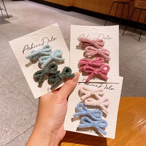 Detail of plush bow hair clips in multiple colors on a branded display card