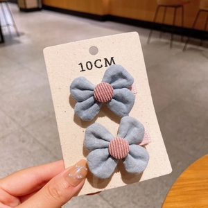 Detailed close-up of a large 10cm blue fabric bow hair clip with pink corduroy button accent