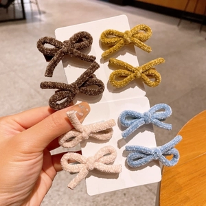Detail of four pairs of plush faux lamb wool bow hair clips in assorted warm colors