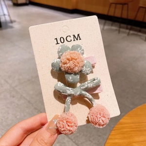 Detail view of 10cm floral hair clip and pompom bow tie accessory set on card board