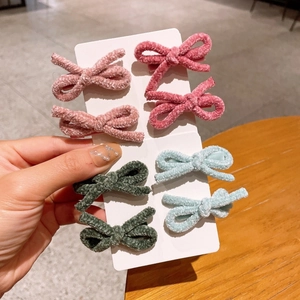Detailed view of six fuzzy lamb wool bow hair clips in multiple pastel colors