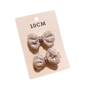Pair of brown checkered bow hair clips for kids on a white 10cm display card