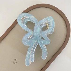 Macro detail of a light blue iridescent butterfly hair claw clip with golden metal spring