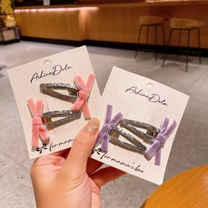 Détail de barrettes à nœuds en velours rose et violet avec finition argentée brillante