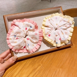 Close-up of colorful heart print scrunchies with pink ruffled edges on a wooden tray